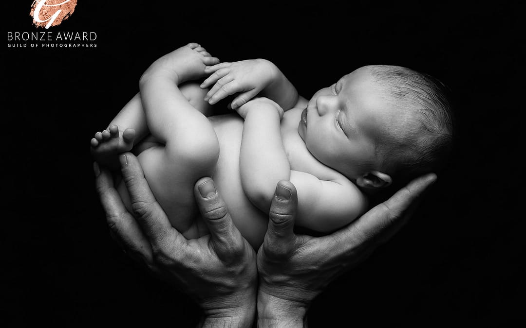 Award winning newborn photographer sutton coldfield, black and white image of newborn baby in dad's hands. Newborn photo taken by Sutton Coldfield newborn photographer Nicki Byrne Photography, newborn photographer birmingham