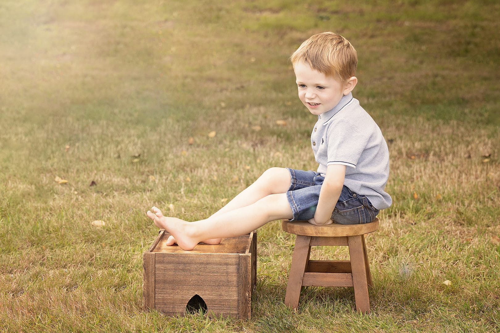Child portraits - young boy sat on a crate outdoors in the sun rays.  Taken by Sutton Coldfield Family photographer, Nicki Byrne Photography, birmingham