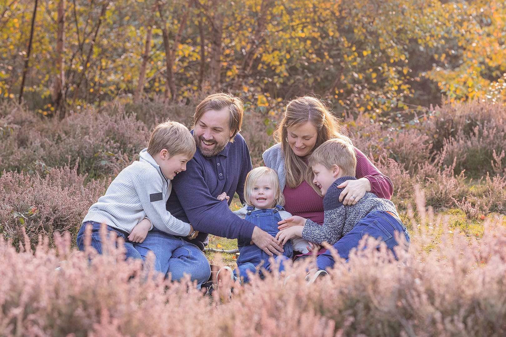 Outdoors, surrounded by heather, a family of five are naturally having fun. Taken by family photographer Nicki Byrne Photography, Family photographer Sutton Coldfield Birmingham
