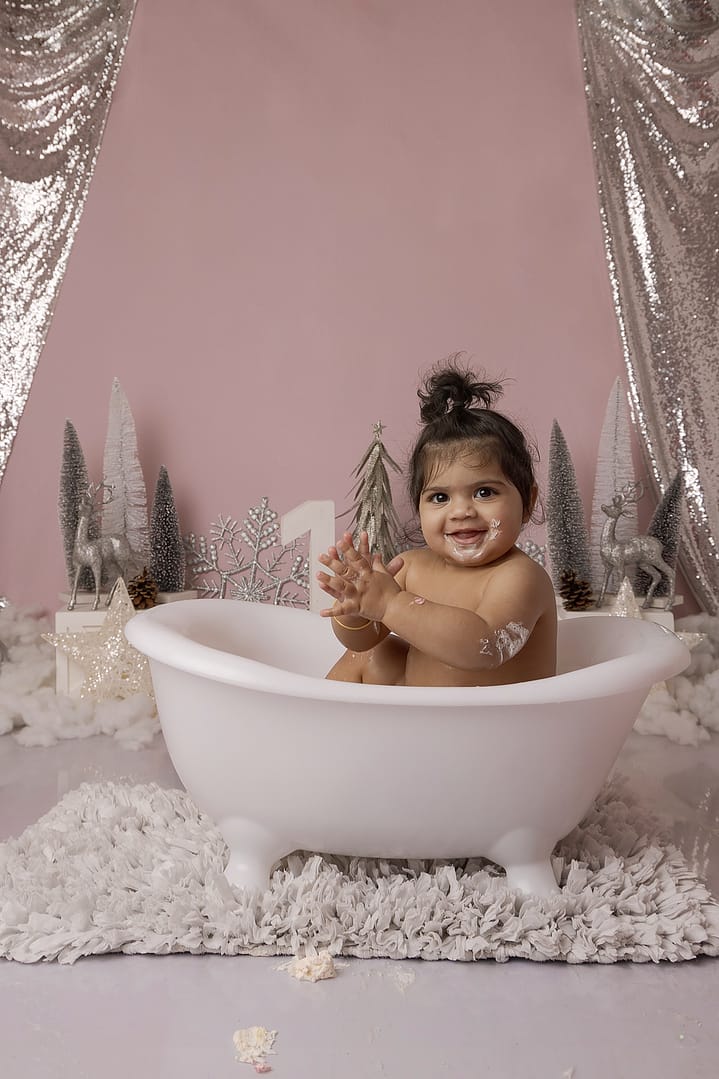 Beautiful girl enjoying her bubble bath in a Winter Onederland theme with pink and silver, during her cake smash in Sutton Coldfield Birmingham