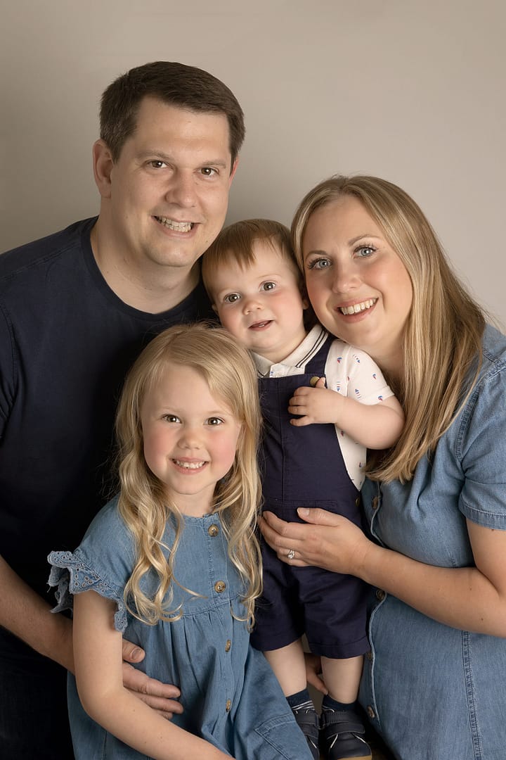 Family of four posing in the Sutton Coldfield photography studio at the youngest boy's cake smash.  Taken by Nicki Byrne Photography, cake smash and family photographer Sutton Coldfield birmingham