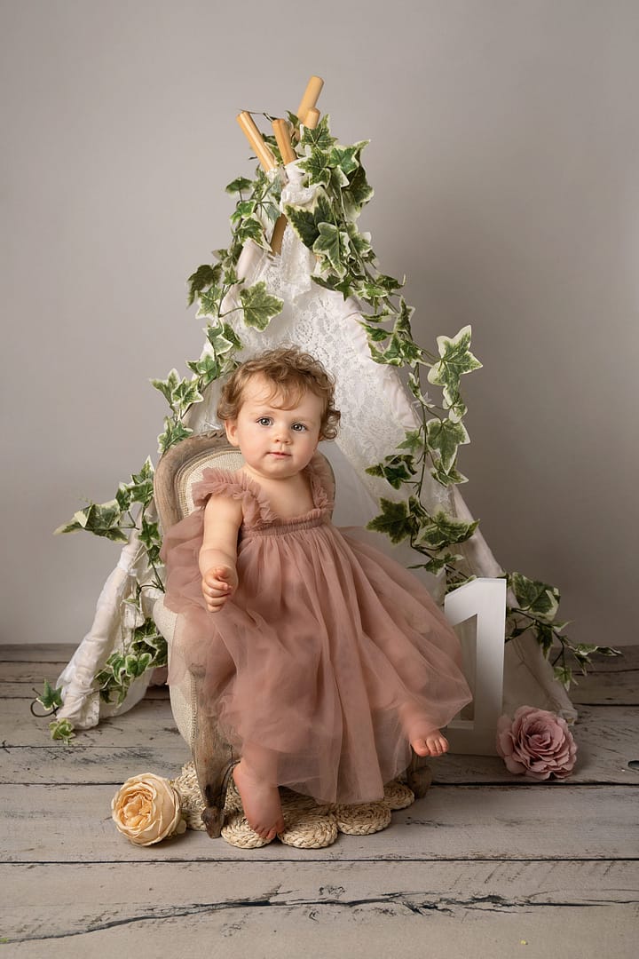 one year old girl sat in a small arm chair during her cake smash, photographer Sutton Coldfield birmingham