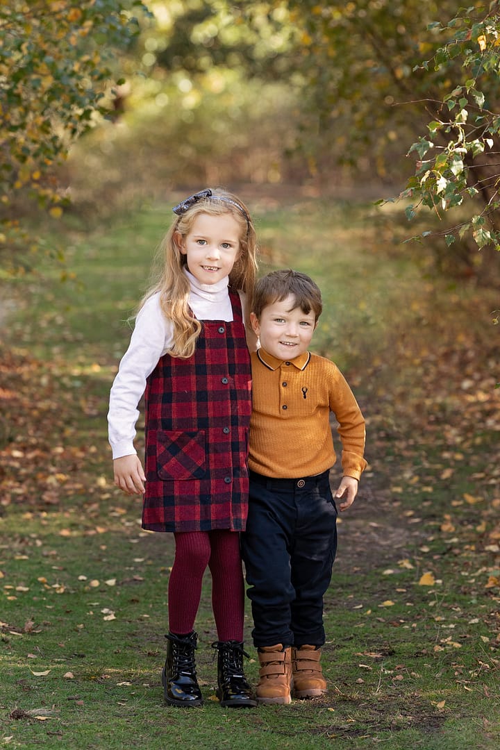 Surrounded by trees in the park, this autumn mini session with two small children looking directly at the camera and smiling naturally.  Taken by Family photographer Nicki Byrne Photography, Sutton Coldfield Birmingham