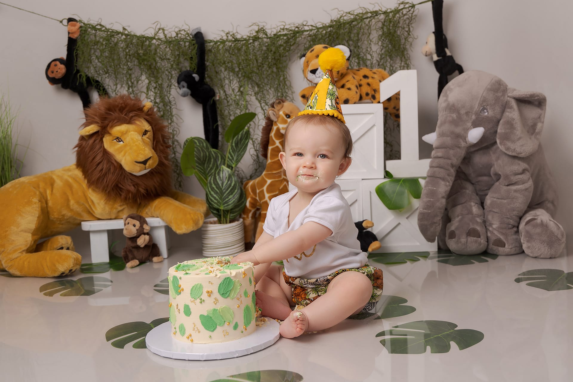 One year old with a jungle themed cake smash set about to break open into her cake